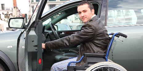 Homme en fauteuil roulant ouvre la portière de sa voiture
